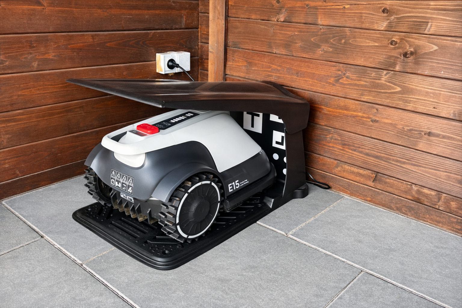 eufy E15 Erfahrung – Mähroboter in der Ladestation am Holzzaun